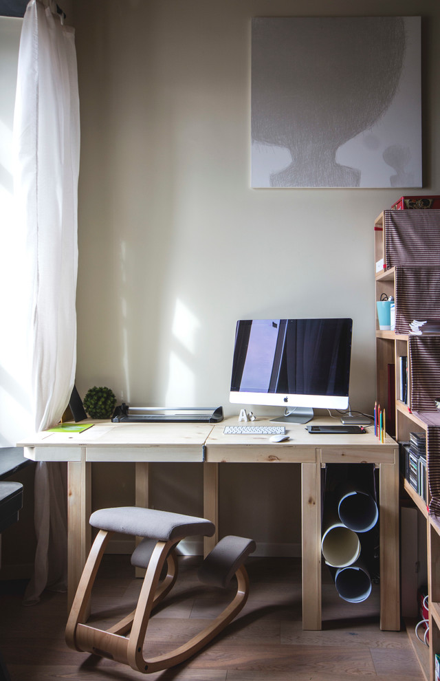 Kleines Modernes Arbeitszimmer mit beiger Wandfarbe, hellem Holzboden und Arbeitsplatz in Mailand