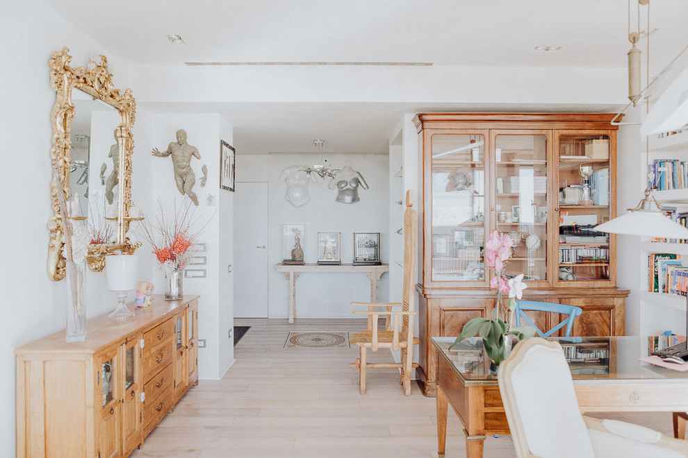 Immagine di uno studio tradizionale con parquet chiaro, libreria, pareti bianche, scrivania autoportante e pavimento beige