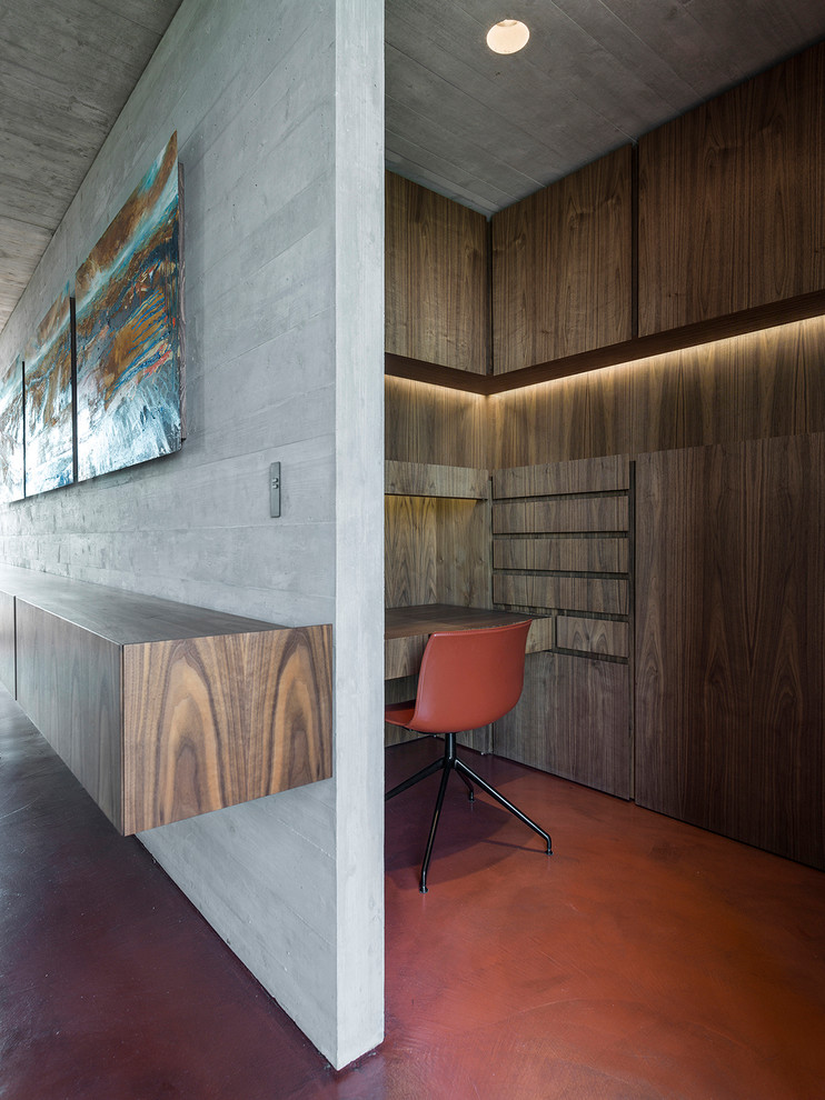 Réalisation d'un petit bureau design de type studio avec sol en béton ciré, un bureau intégré et un sol rouge.