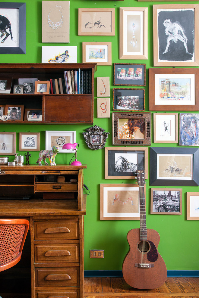Eklektisches Arbeitszimmer mit Arbeitsplatz, grüner Wandfarbe, braunem Holzboden und freistehendem Schreibtisch in Mailand