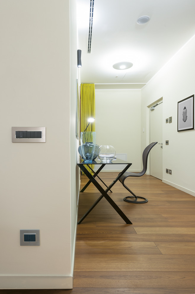 Ispirazione per uno studio minimalista con pavimento in legno verniciato e scrivania autoportante