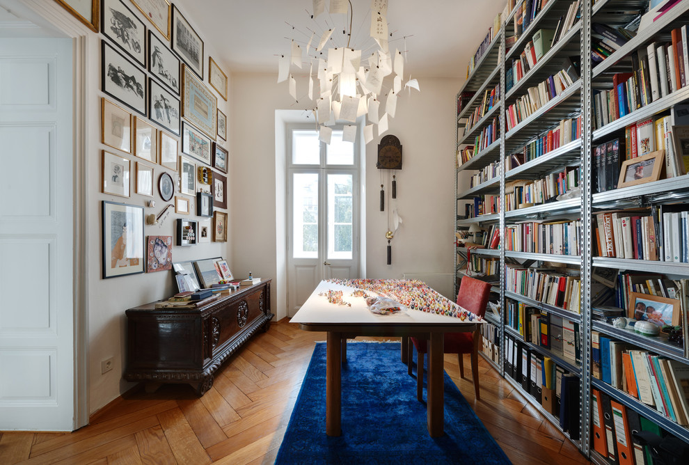 Idéer för ett eklektiskt arbetsrum, med ett bibliotek, vita väggar, mellanmörkt trägolv och ett fristående skrivbord