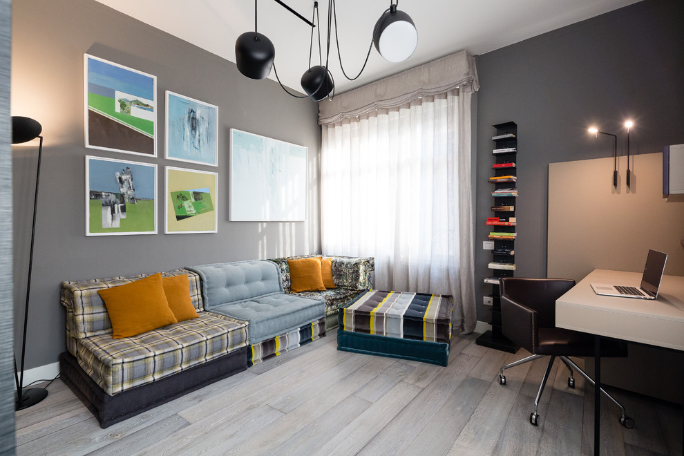 This is an example of an expansive bohemian craft room in Milan with grey walls, dark hardwood flooring, a two-sided fireplace, a concrete fireplace surround, a freestanding desk and grey floors.