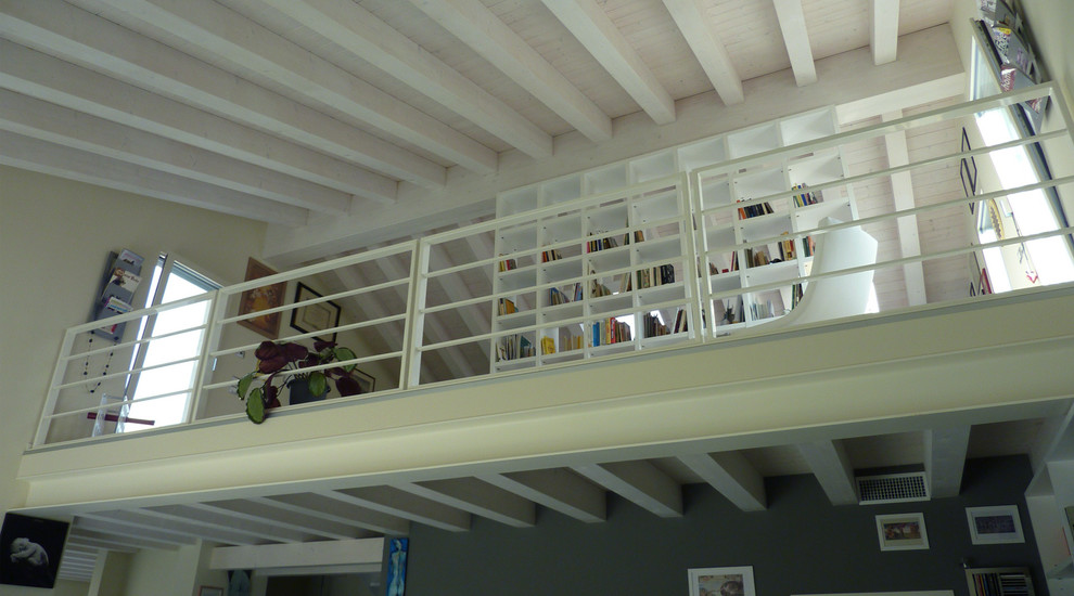 Modelo de despacho grande con biblioteca, paredes blancas, suelo de madera en tonos medios, escritorio empotrado y suelo beige