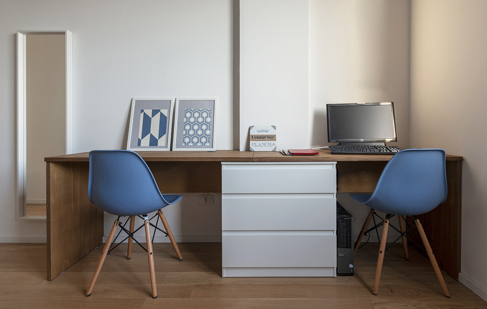 Imagen de estudio actual pequeño sin chimenea con paredes blancas, suelo de madera clara, escritorio independiente y suelo beige