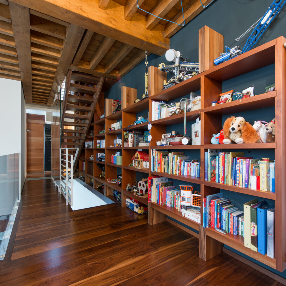 Idee per uno studio design di medie dimensioni con libreria, pareti blu, pavimento in legno verniciato e pavimento marrone