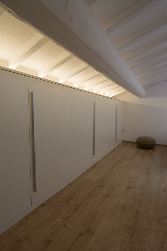 Minimalistisk inredning av ett stort hemmastudio, med vita väggar, linoleumgolv, ett fristående skrivbord och beiget golv