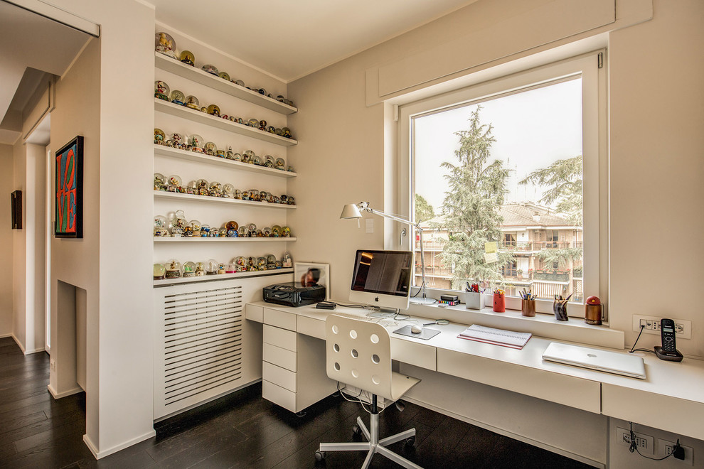 Immagine di uno studio minimal con pareti bianche, parquet scuro, scrivania incassata e pavimento marrone