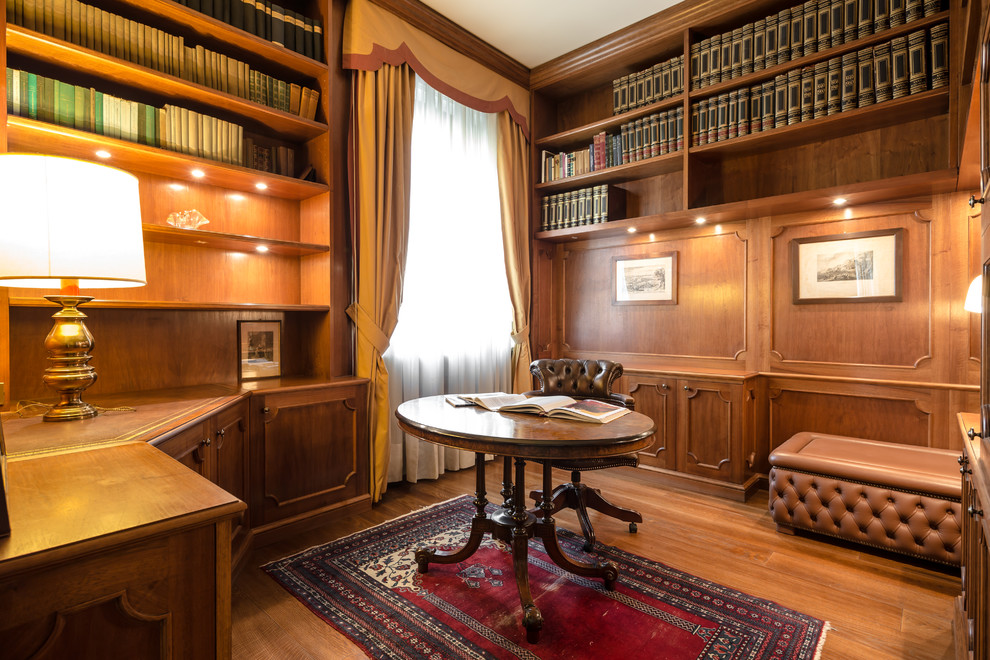 Idee per uno studio classico di medie dimensioni con libreria, pareti marroni, pavimento in legno massello medio, scrivania autoportante e pavimento marrone