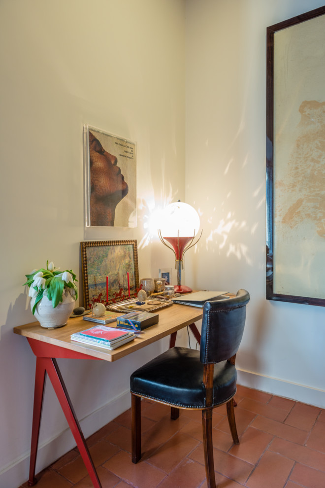 Modelo de despacho bohemio pequeño con paredes blancas, suelo de ladrillo, escritorio independiente y suelo rojo