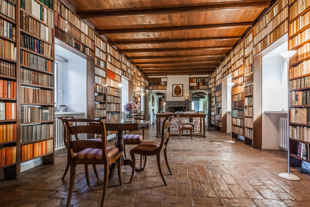 Foto de despacho de estilo de casa de campo con biblioteca, suelo de baldosas de terracota y chimenea de doble cara