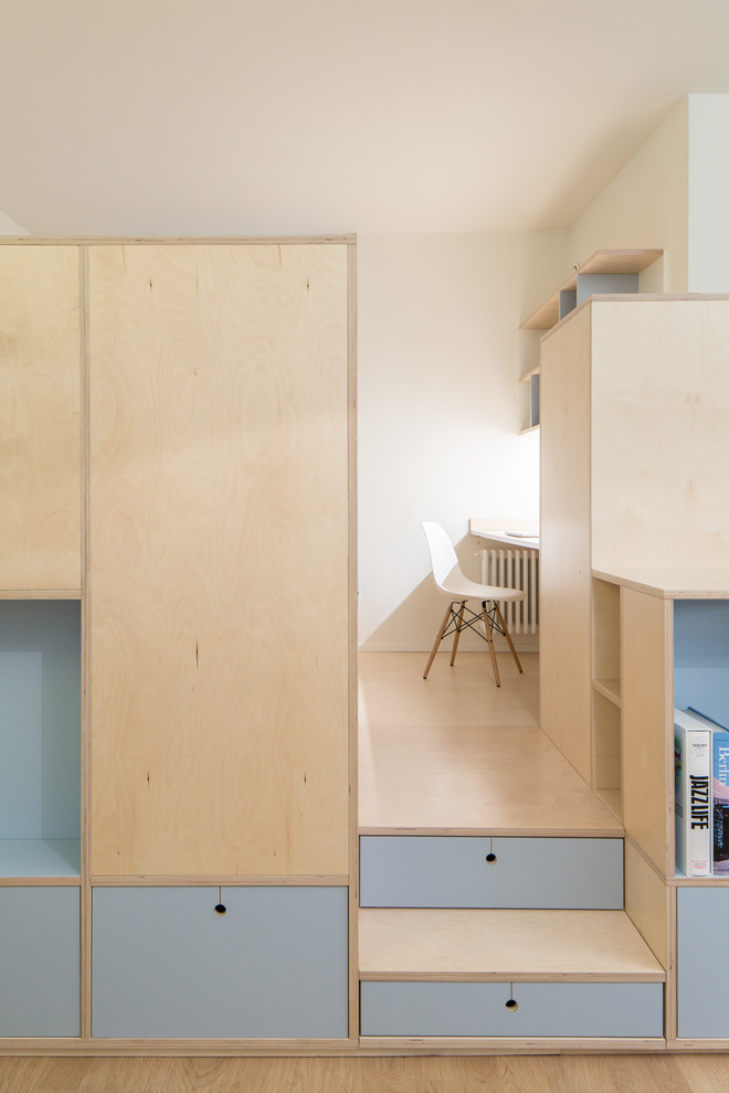Idee per un piccolo atelier nordico con pareti bianche, pavimento in legno massello medio e scrivania incassata