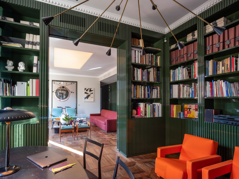 Idee per un grande studio minimal con libreria, pareti verdi, parquet scuro, camino classico, cornice del camino in metallo, scrivania autoportante e pavimento marrone