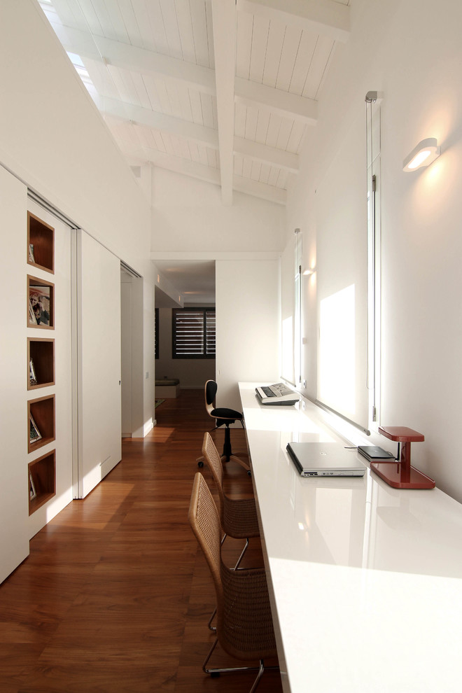 Inspiration för ett funkis hemmabibliotek, med vita väggar, mellanmörkt trägolv och ett inbyggt skrivbord