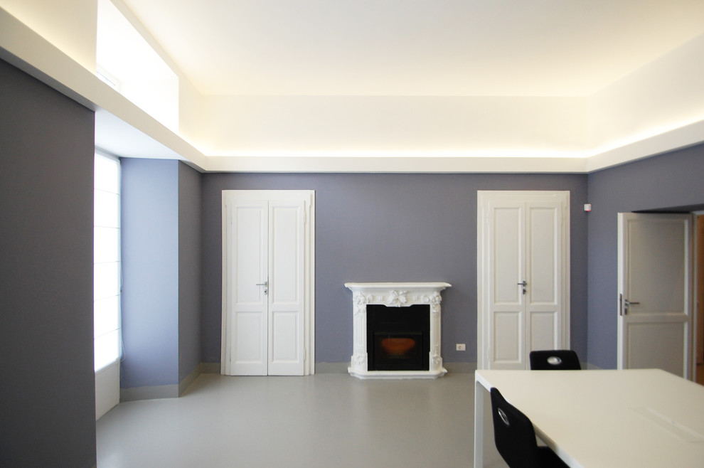 Inredning av ett modernt mellanstort hemmastudio, med grå väggar, betonggolv, en standard öppen spis, en spiselkrans i betong, ett fristående skrivbord och grått golv