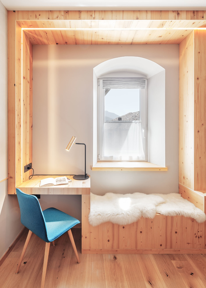 На фото: кабинет в стиле модернизм с белыми стенами, паркетным полом среднего тона и встроенным рабочим столом