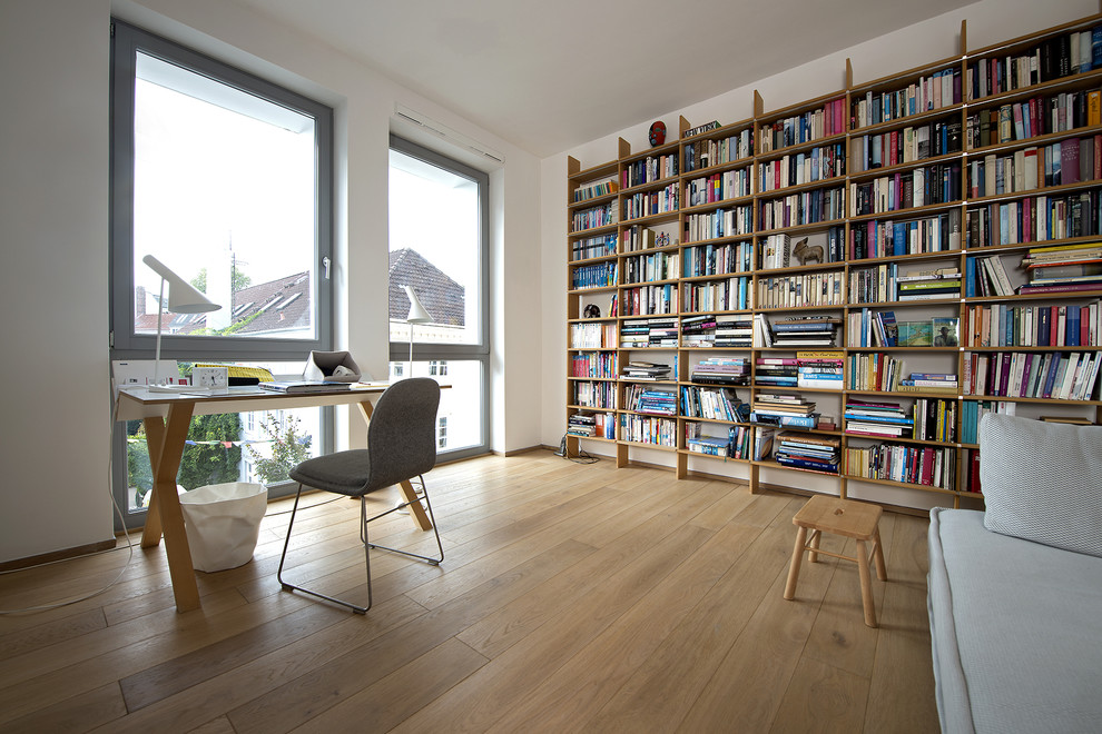 Skandinavisches Arbeitszimmer mit Arbeitsplatz, weißer Wandfarbe, hellem Holzboden und freistehendem Schreibtisch in Mailand