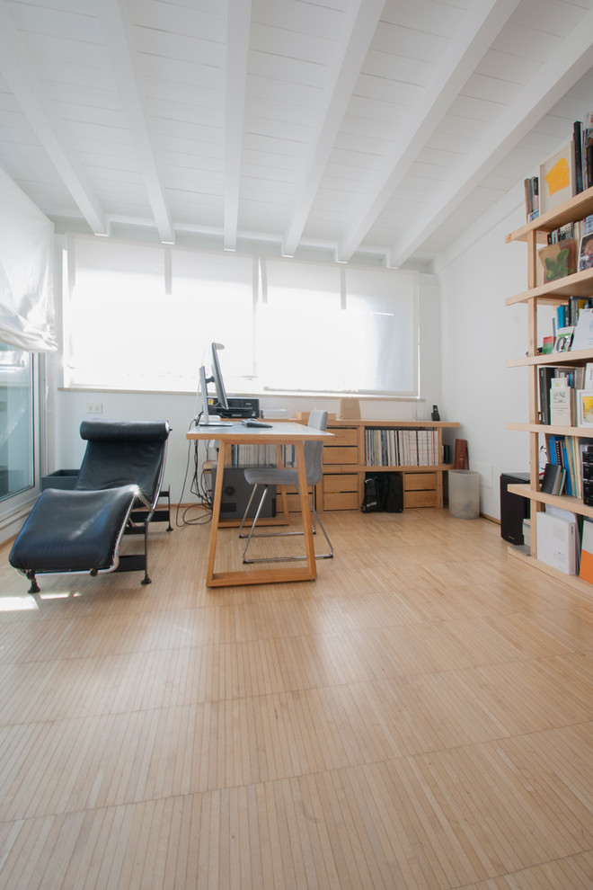 Inredning av ett modernt mellanstort hemmastudio, med vita väggar, ljust trägolv och ett fristående skrivbord