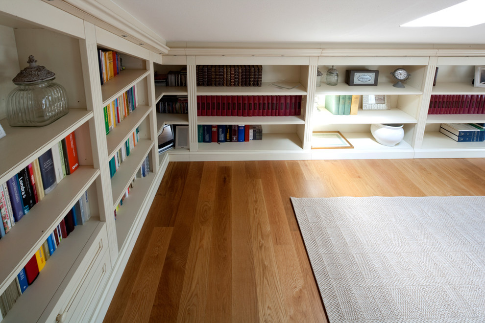 Foto di un grande studio minimal con libreria, pareti beige, pavimento in legno massello medio e pavimento marrone
