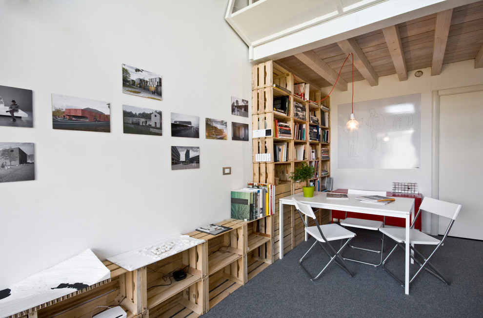 Inredning av ett modernt litet hemmastudio, med vita väggar, heltäckningsmatta och ett fristående skrivbord