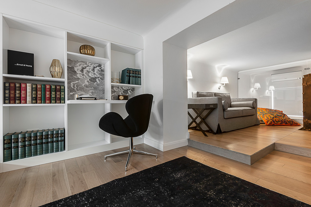 Cette image montre un bureau minimaliste de taille moyenne et de type studio avec un mur blanc, parquet clair, un bureau intégré et un sol marron.