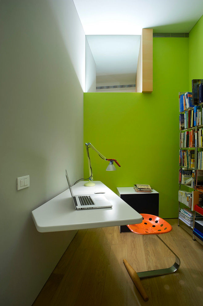 Modern inredning av ett litet arbetsrum, med gröna väggar, ljust trägolv och ett fristående skrivbord