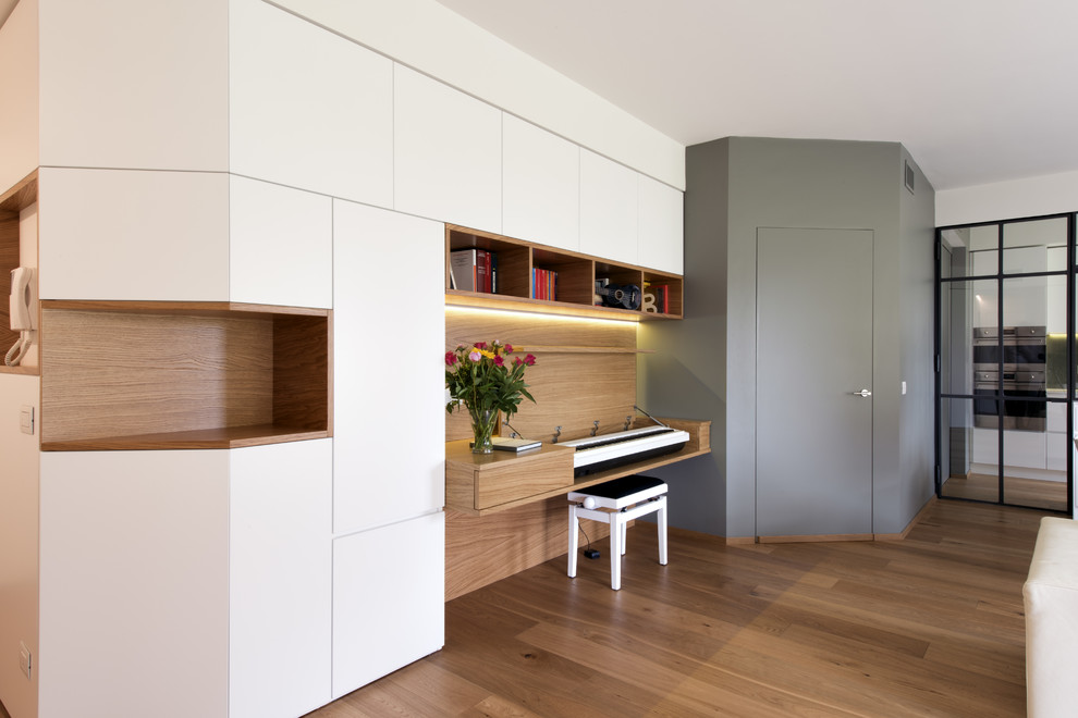 Foto de despacho minimalista grande con biblioteca, paredes blancas, suelo de madera clara y suelo beige