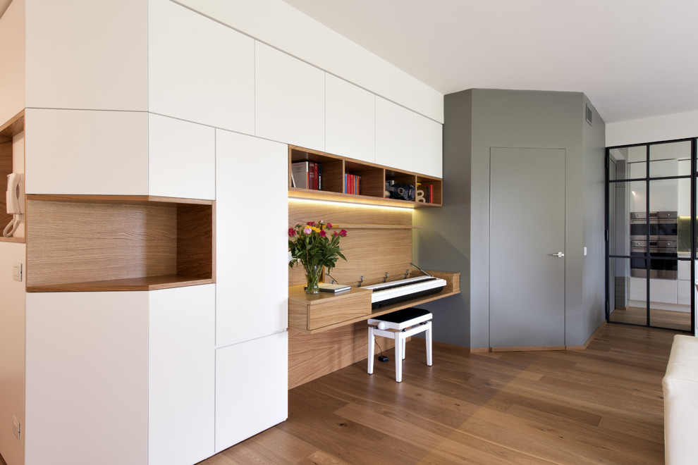 This is an example of a large modern home office in Milan with a reading nook, white walls, light hardwood flooring and beige floors.