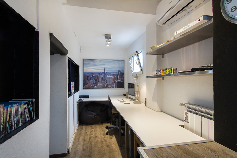 Mittelgroßes Modernes Arbeitszimmer mit Studio, weißer Wandfarbe, braunem Holzboden und freistehendem Schreibtisch in Mailand