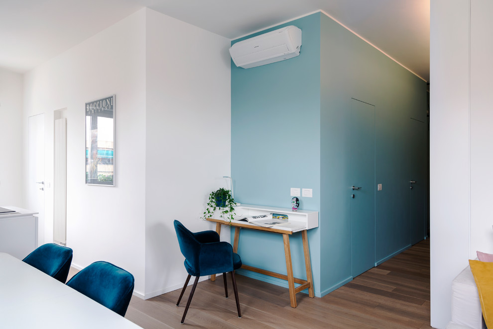 Foto de estudio contemporáneo pequeño con paredes azules, suelo de madera en tonos medios y escritorio independiente