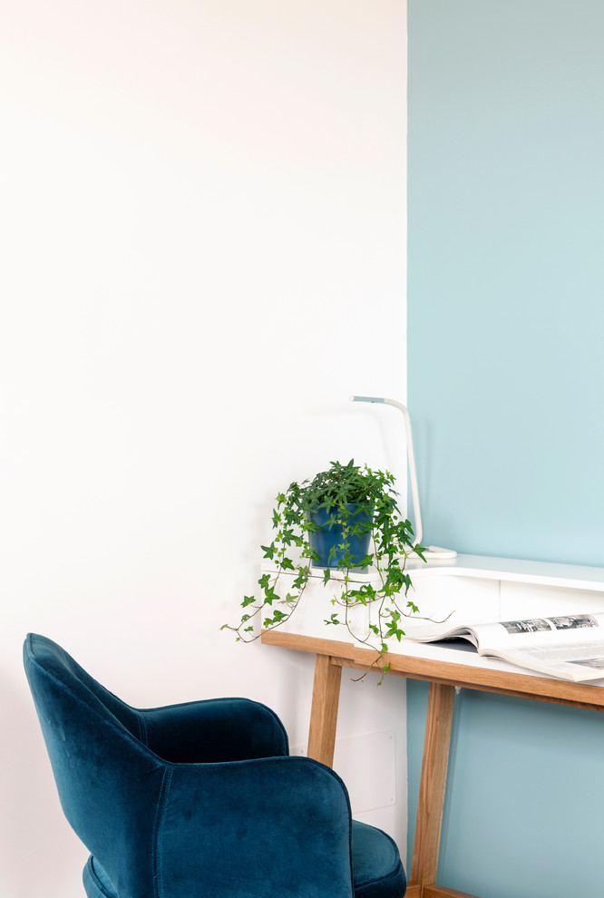 Immagine di un piccolo atelier minimal con pareti blu, pavimento in legno massello medio e scrivania autoportante