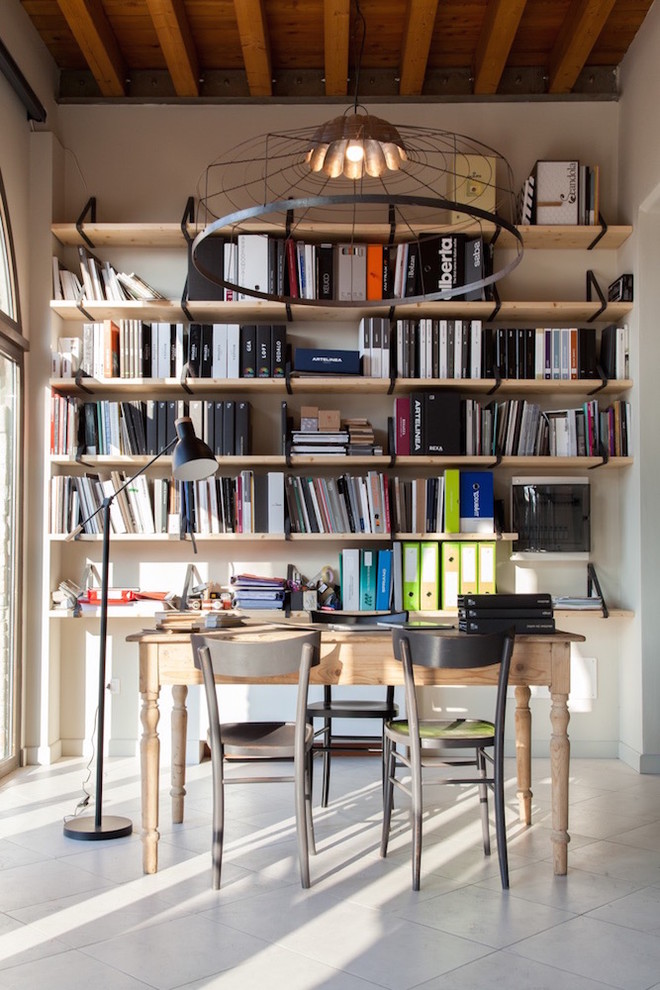 Immagine di uno studio industriale di medie dimensioni con libreria, pareti bianche e scrivania autoportante