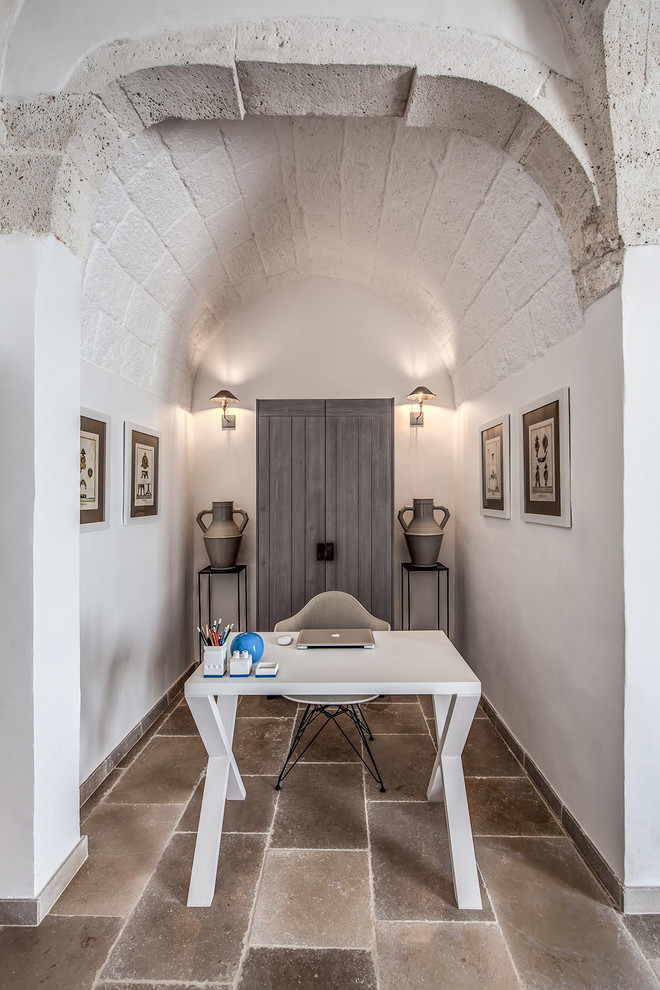 Diseño de despacho mediterráneo con paredes blancas, escritorio independiente y suelo marrón
