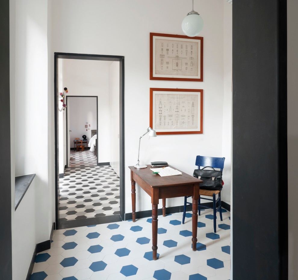 Inredning av ett minimalistiskt arbetsrum, med vita väggar, ett fristående skrivbord och klinkergolv i keramik