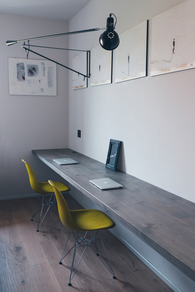 Mittelgroßes Modernes Arbeitszimmer mit Studio, weißer Wandfarbe, dunklem Holzboden und Einbau-Schreibtisch in Mailand