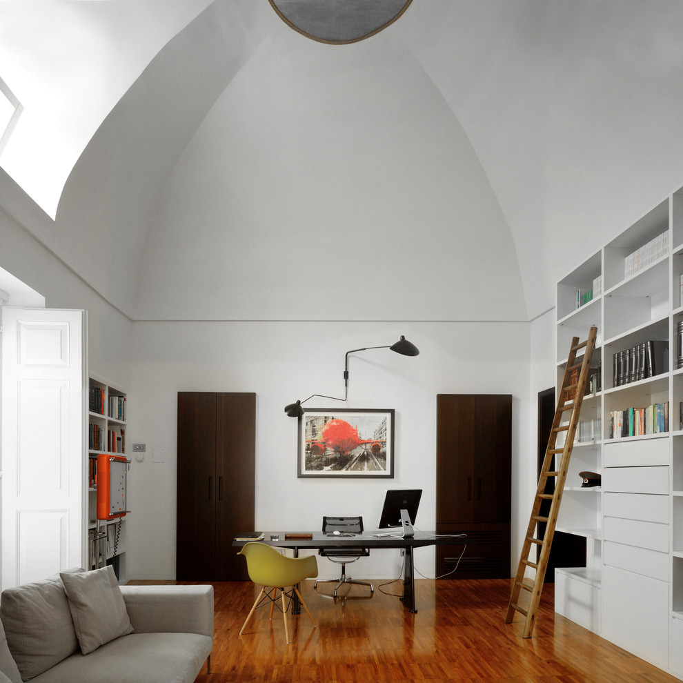 Photo of a contemporary study in Other with white walls, medium hardwood flooring, a freestanding desk and brown floors.