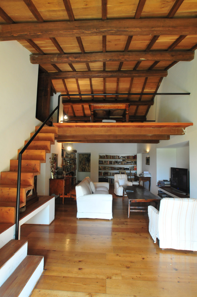 Diseño de estudio de tamaño medio con paredes blancas, suelo de madera en tonos medios y suelo marrón