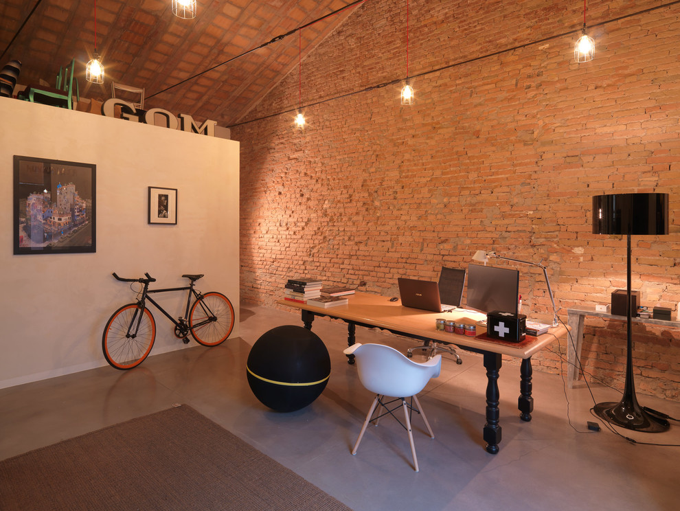 ボローニャにある中くらいなインダストリアルスタイルのおしゃれなアトリエ・スタジオ (茶色い壁、コンクリートの床、暖炉なし、自立型机、グレーの床) の写真