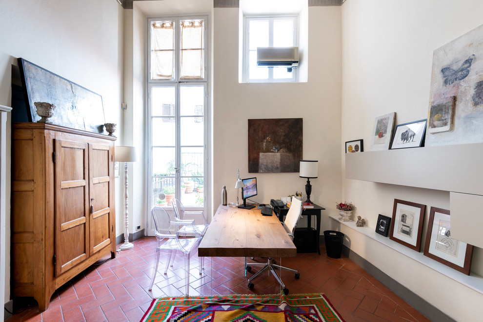 Imagen de despacho moderno grande sin chimenea con paredes blancas, suelo de baldosas de terracota, escritorio independiente y suelo marrón