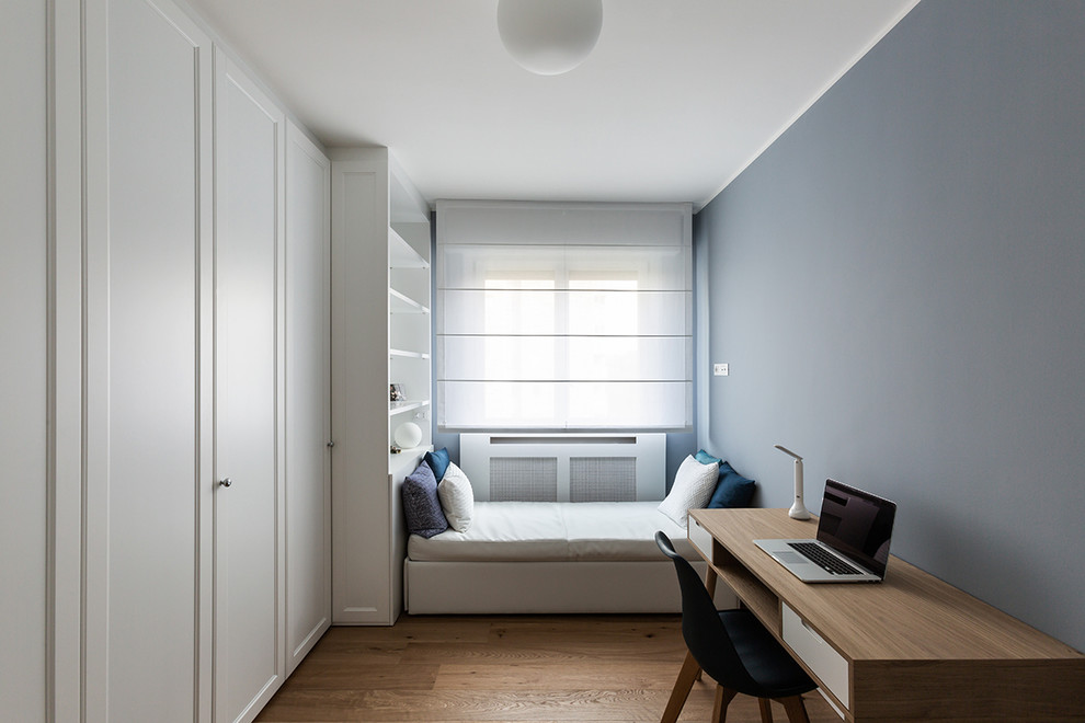 Esempio di un atelier minimalista di medie dimensioni con pareti blu, parquet chiaro e scrivania autoportante