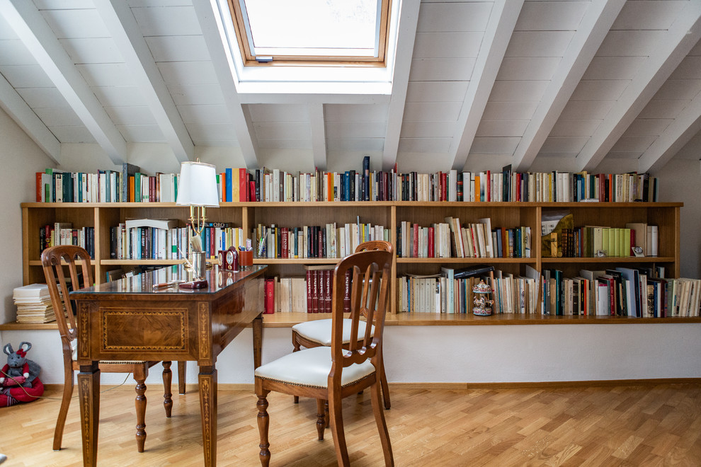 Klassisches Lesezimmer mit weißer Wandfarbe, freistehendem Schreibtisch, braunem Boden und hellem Holzboden in Mailand