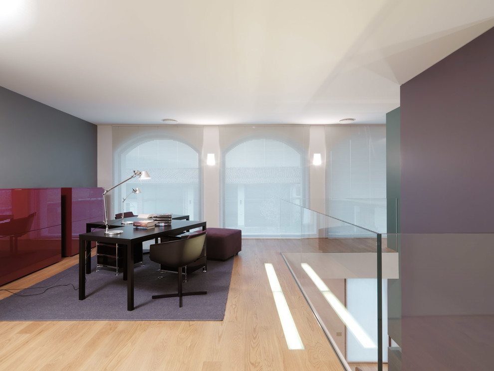 Foto de estudio contemporáneo grande con paredes multicolor, suelo de madera clara y escritorio independiente