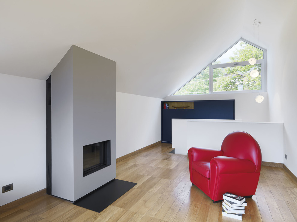 Inspiration for a medium sized contemporary home studio in Turin with white walls, medium hardwood flooring, a plastered fireplace surround and a standard fireplace.