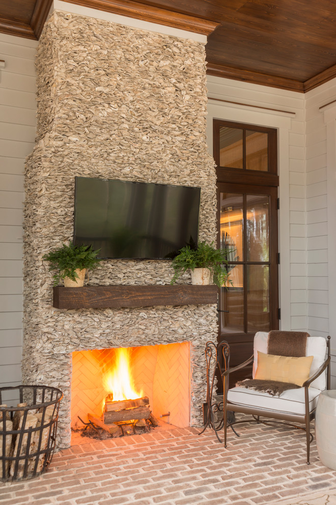 Cette photo montre une grande véranda chic avec un sol en brique, une cheminée standard, un plafond standard et un manteau de cheminée en brique.