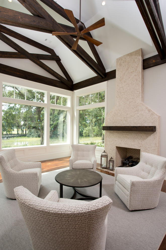 Idée de décoration pour une grande véranda tradition avec un sol en bois brun, une cheminée standard, un manteau de cheminée en pierre et un plafond standard.