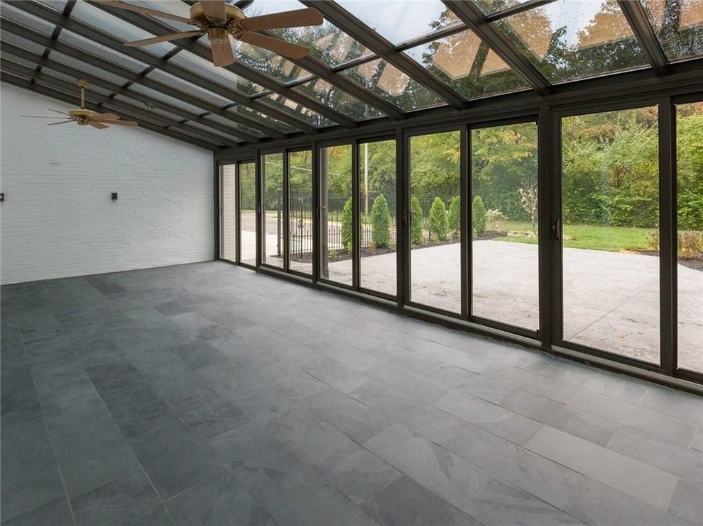 Idée de décoration pour une véranda design avec un sol en calcaire, un plafond en verre et un sol gris.