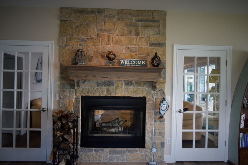他の地域にあるトラディショナルスタイルのおしゃれなサンルーム (無垢フローリング、両方向型暖炉、石材の暖炉まわり、茶色い床) の写真