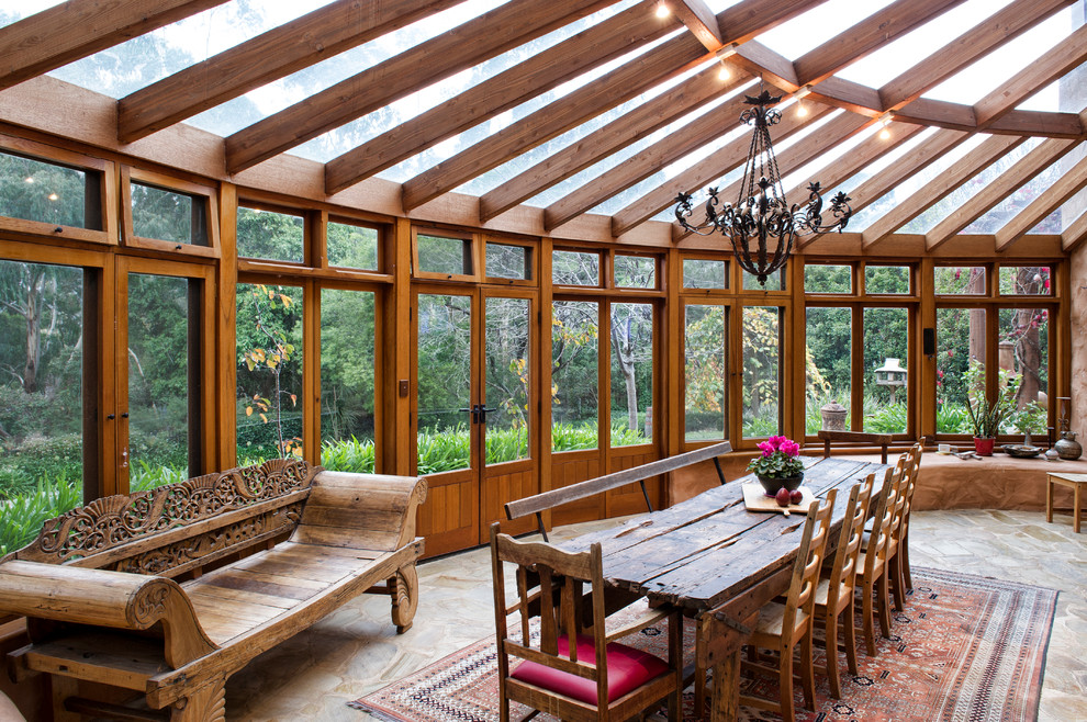Foto di una grande veranda rustica con soffitto in vetro, pavimento in ardesia e nessun camino
