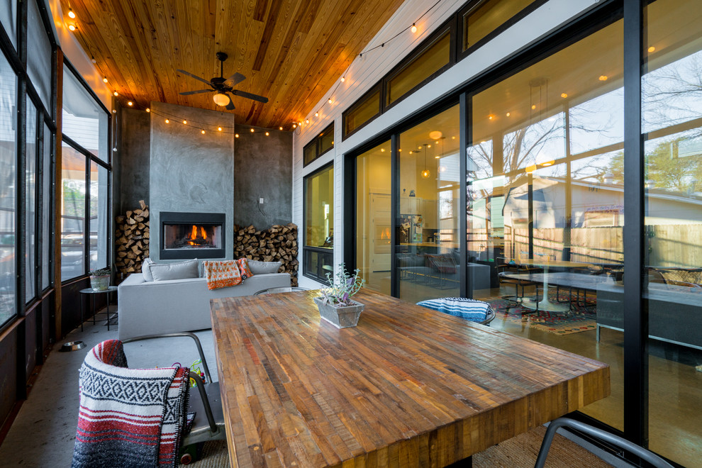 オースティンにあるコンテンポラリースタイルのおしゃれなサンルーム (コンクリートの床、標準型暖炉、標準型天井) の写真