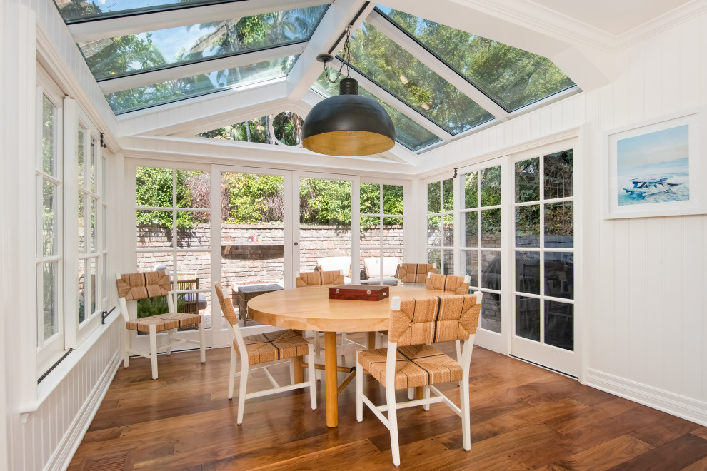 Immagine di una veranda costiera con pavimento in legno massello medio, soffitto in vetro e pavimento marrone